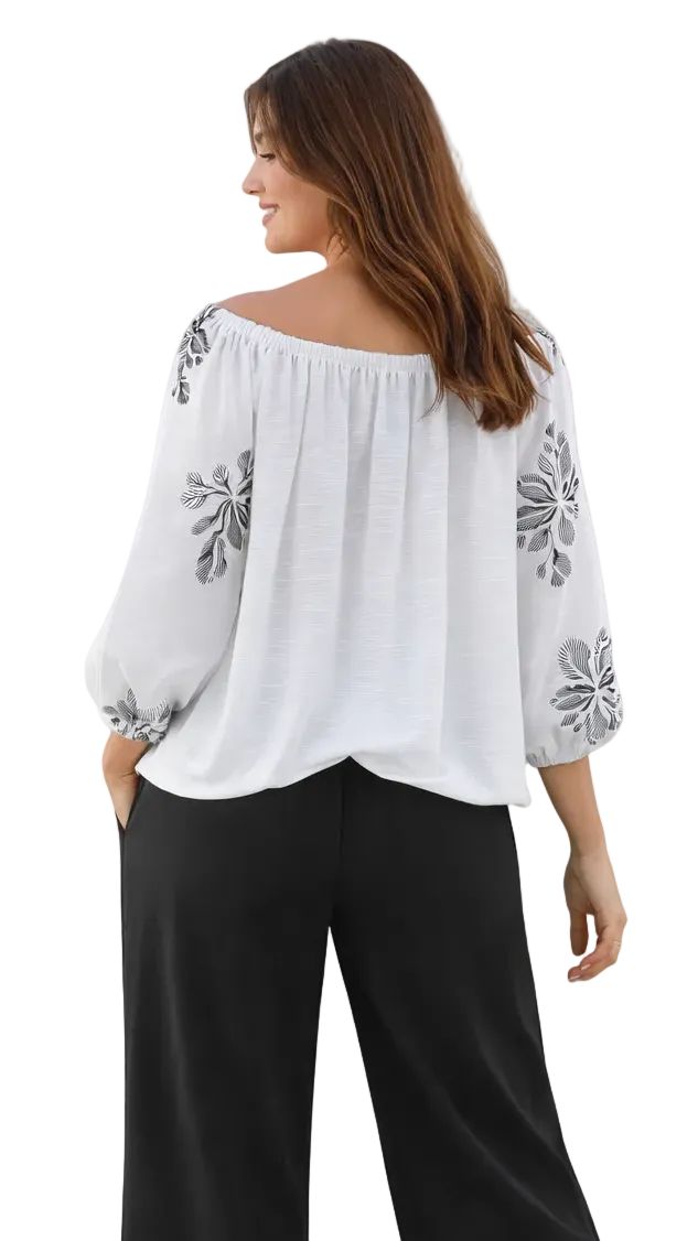 Back view of Woman wearing a white blouse with floral embroidery and black pants on a white background
