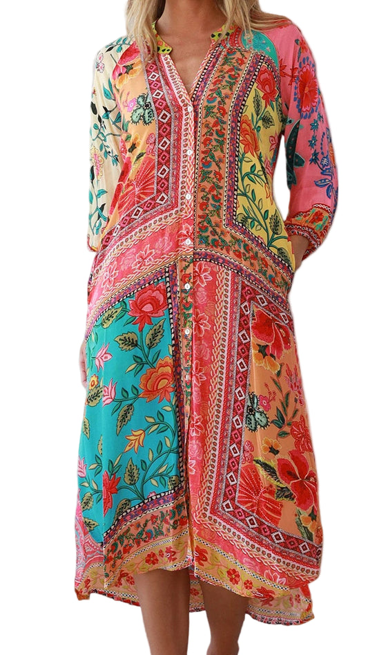 Woman wearing a colorful dress with a decorative hat and floral arrangement indoors.