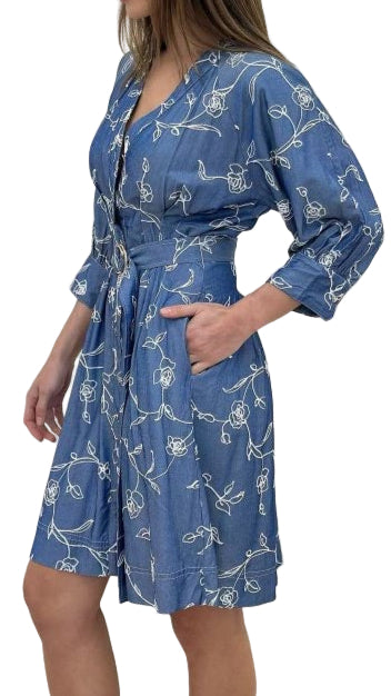 Woman wearing a blue dress with a white floral pattern against a plain background