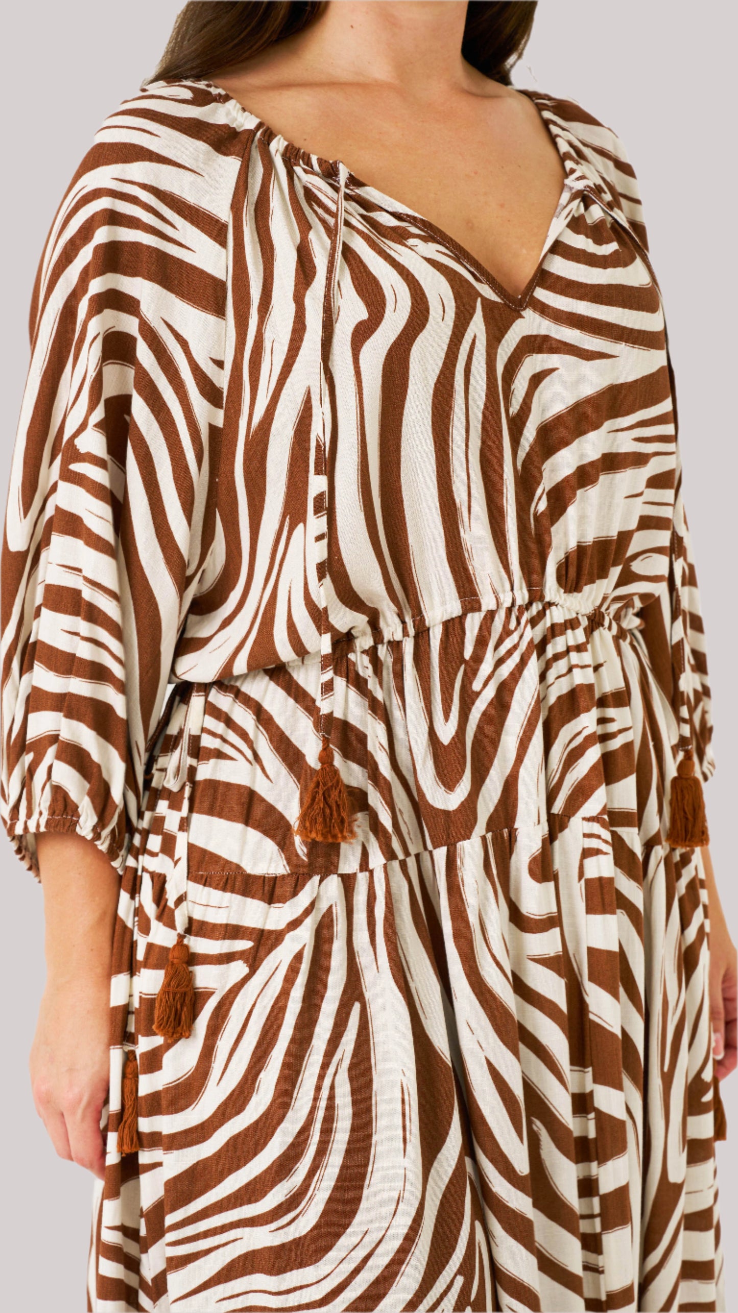 Close-up of zebra print fabric, V-neckline with tassel ties, and adjustable waist.