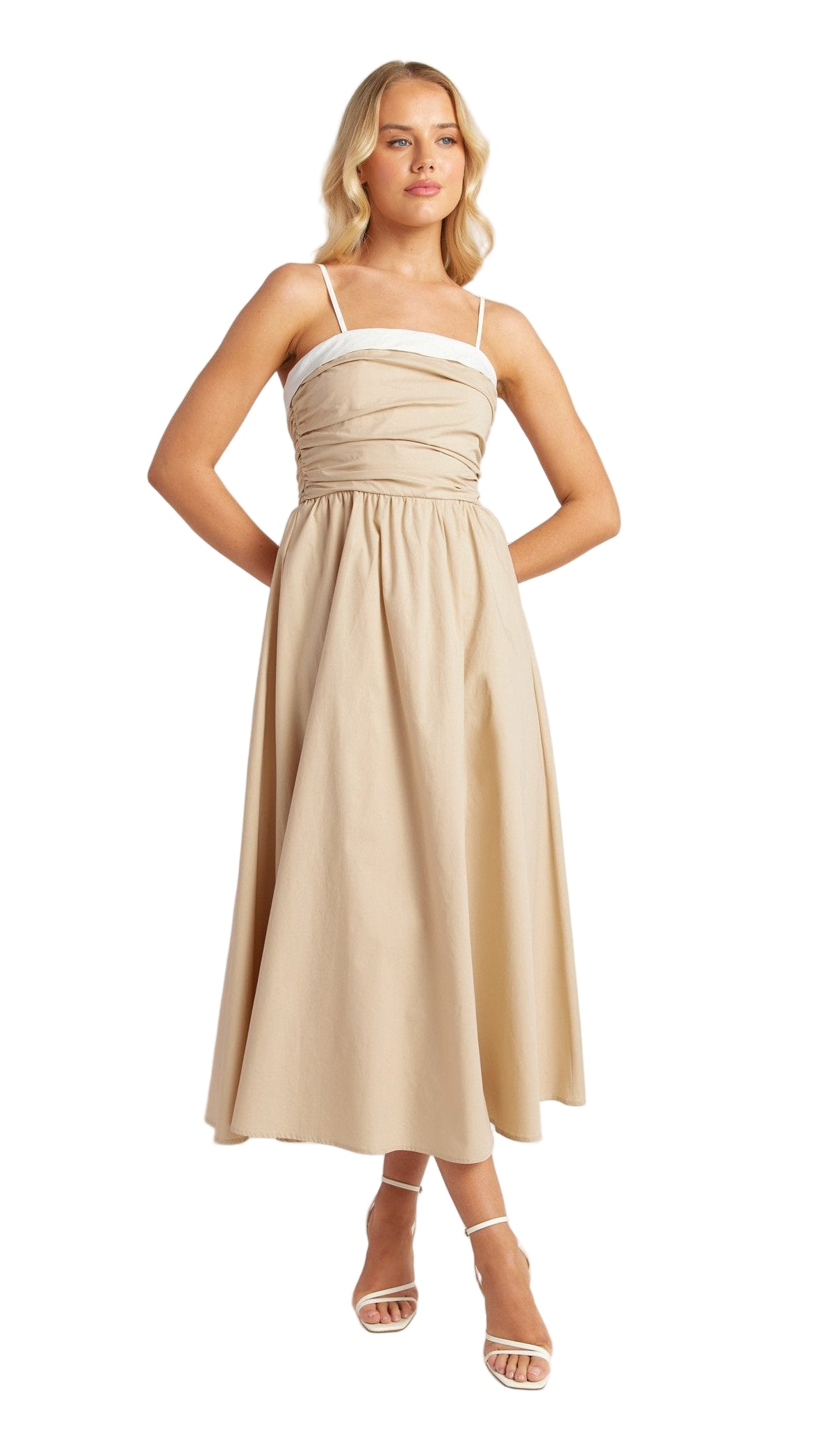 A woman standing and modeling a beige, strapless, A-line midi dress with a gathered waistline and a ruched fitted bodice.