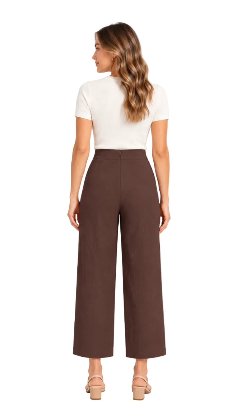 A woman shown from the back wearing high-waisted, wide-leg brown pants, a white short-sleeve top, and beige heeled sandals against a plain white studio background.