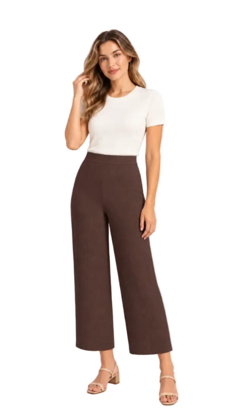 A woman modeling a white short-sleeve crewneck top and dark brown wide-leg cropped pants, paired with beige heeled sandals, against a plain white studio background.