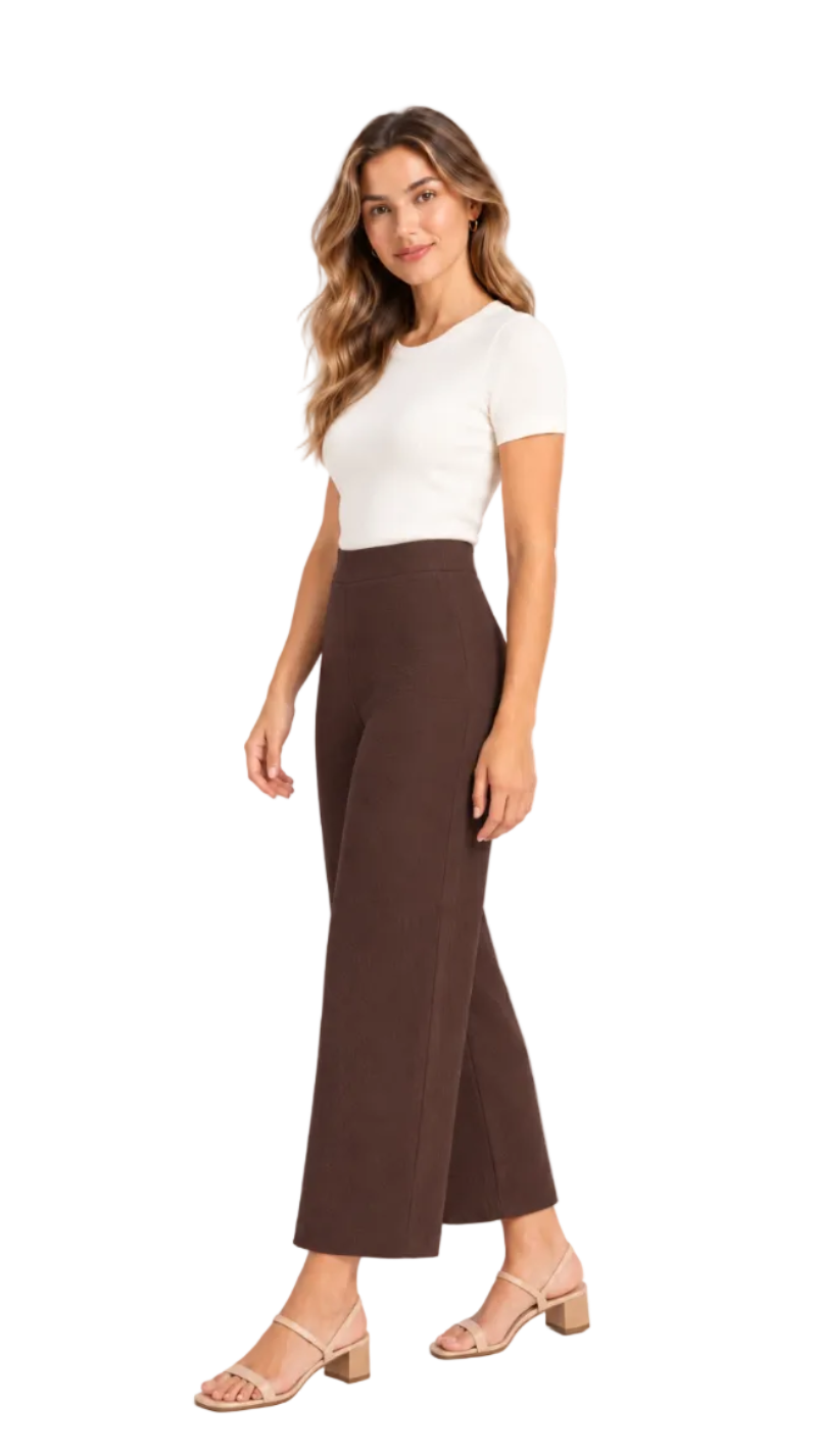 A woman modeling a white short-sleeve knit top and high-waisted, wide-leg brown pants against a clean white studio background.