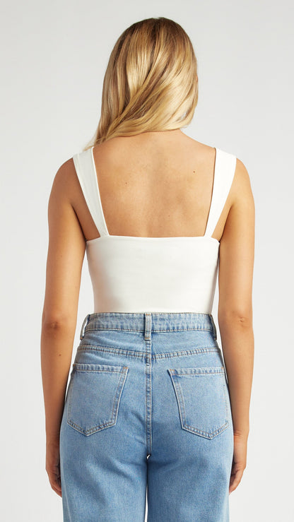 Back view of the Bowline Bodysuit in white highlighting the elegant square back design paired with jeans.