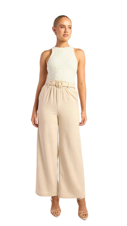Woman wearing a white sleeveless top and beige wide-leg pants on a white background