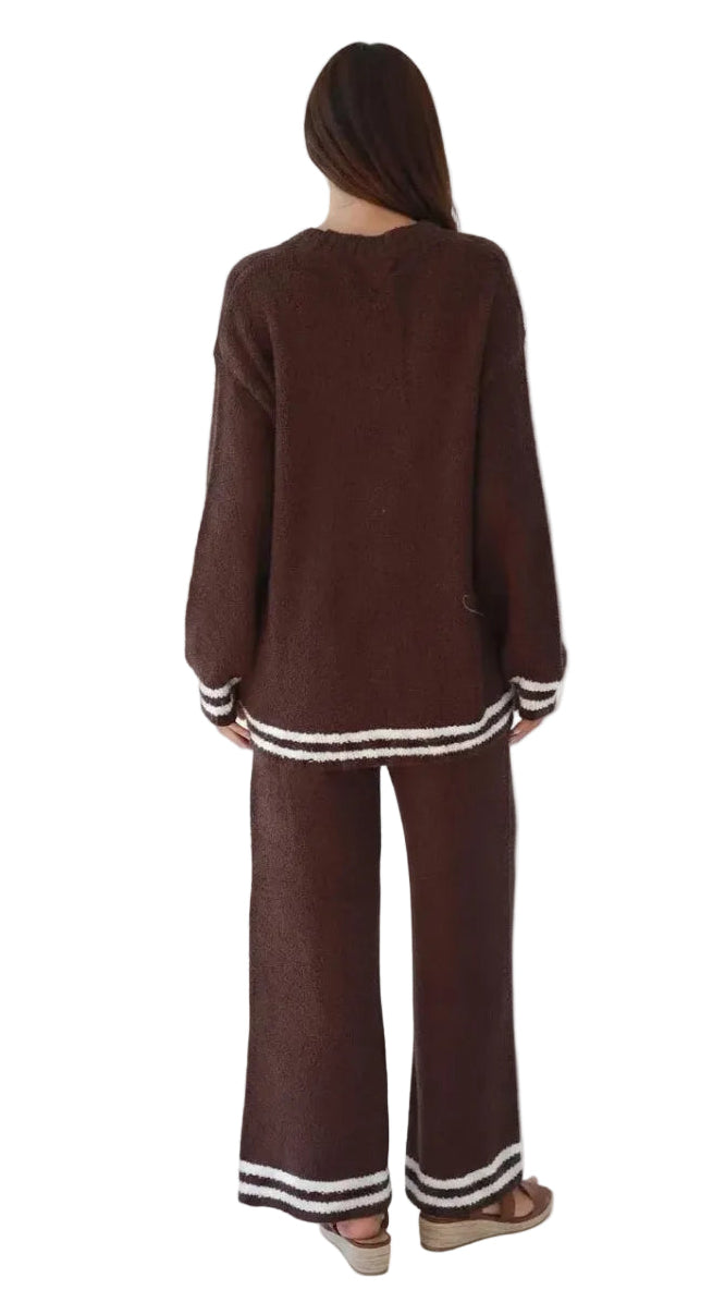 A woman viewed from the back wearing a matching brown knit lounge set with white striped trim on the cuffs and hems, against a plain white background.