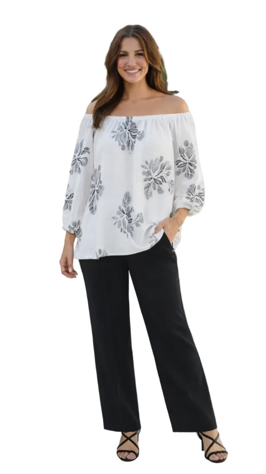 Woman wearing a white blouse with floral patterns and black pants on a white background