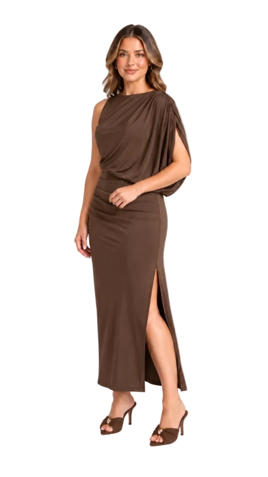 A woman modeling a sleeveless, draped maxi dress in a rich chocolate brown color, featuring a high side slit and matching brown heeled sandals, set against a plain white studio background.
