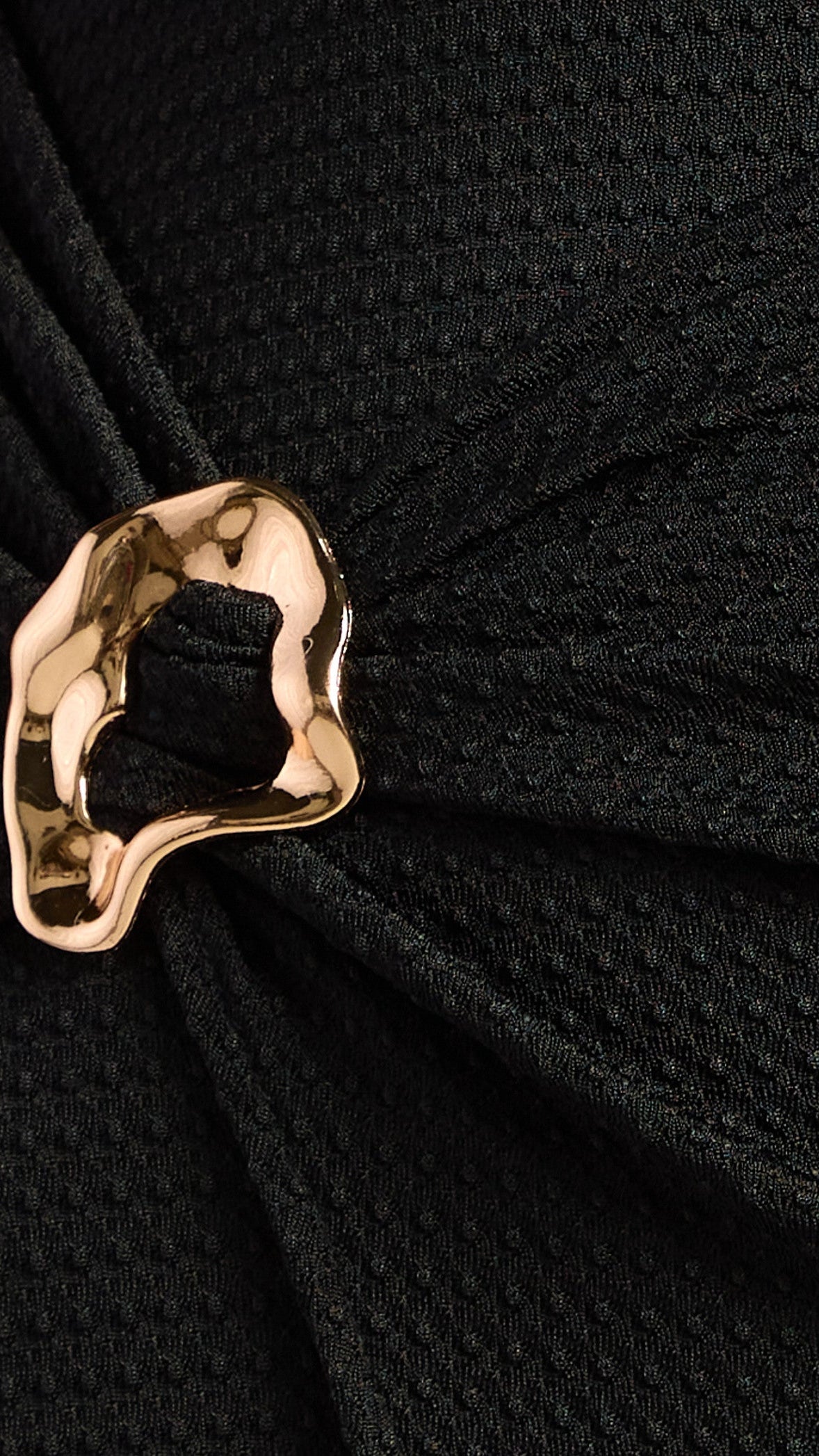 Close-up of a black textured fabric with a gold decorative element.