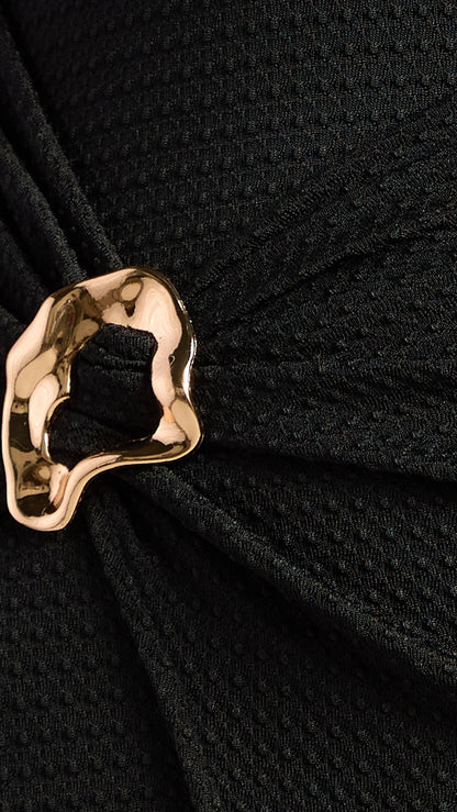 Close-up of a black textured fabric with a gold decorative element.