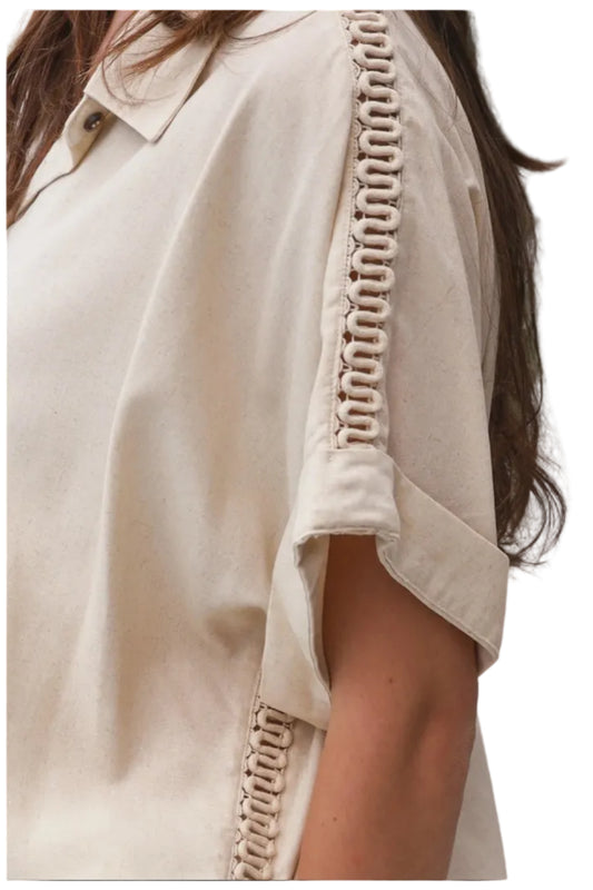 Beige shirt showing delicate trim detail on sleeve and seam