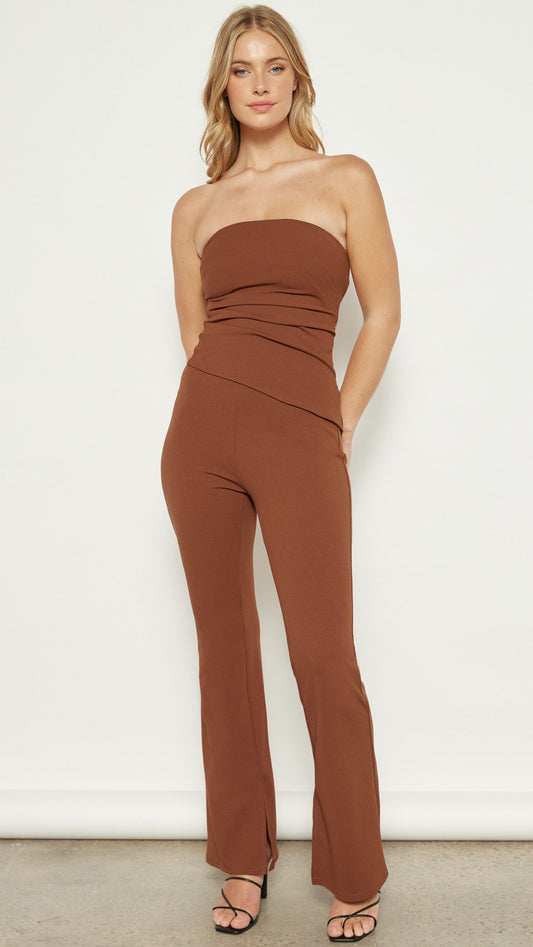 Model wearing the Terra Flare Pants in a rich brick color, standing against a neutral background. The high-waisted fit and flare silhouette are visible.