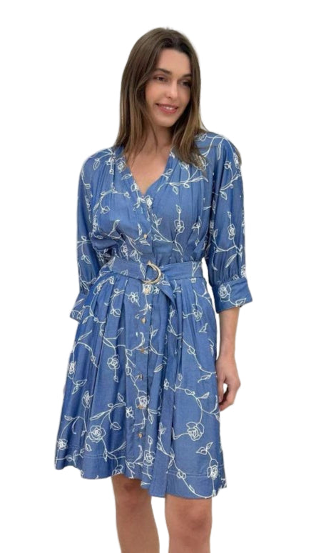 Woman wearing a blue floral dress against a plain background