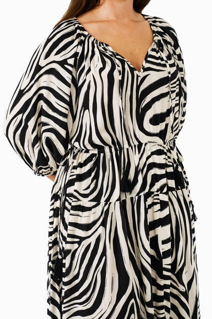 Close-up of zebra print fabric, V-neckline with tassel ties, and adjustable waist.