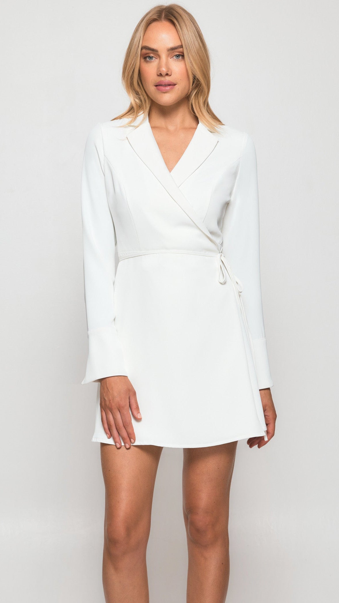 Woman wearing a white blazer dress against a plain background