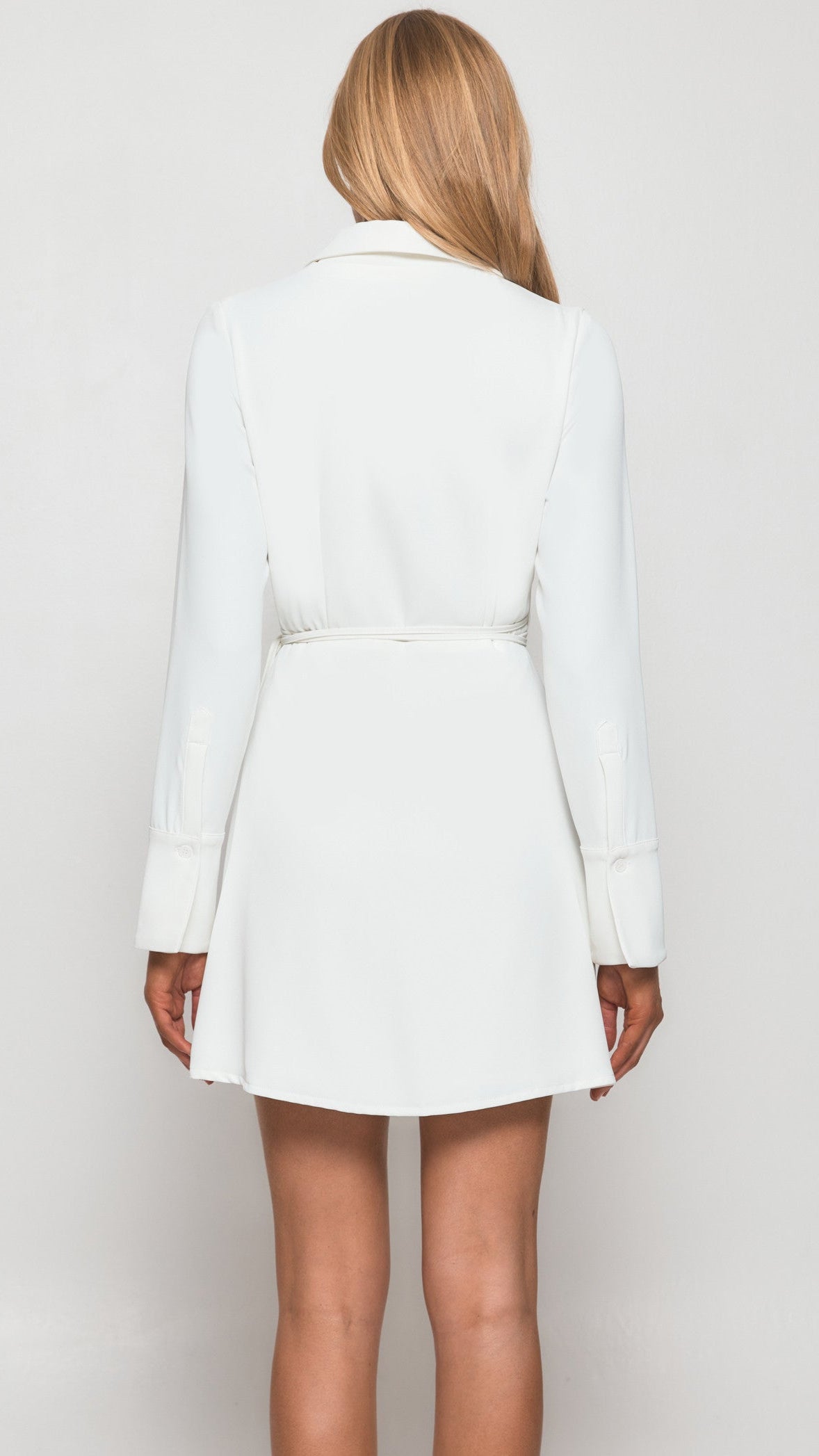 Person wearing a white blazer dress against a plain background